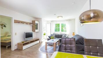 Un salon moderne avec un canapé, un téléviseur et un coin repas.