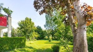 Un jardín con un sendero, árboles y un edificio de techo rojo.