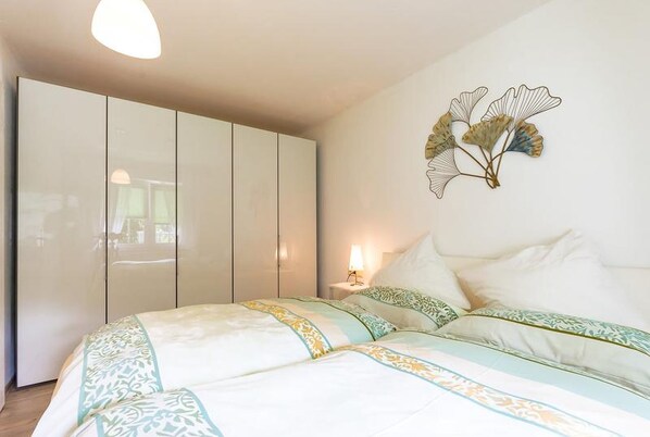 Une chambre à coucher comprenant un lit, une armoire, une lampe de chevet et un élément de décoration murale.