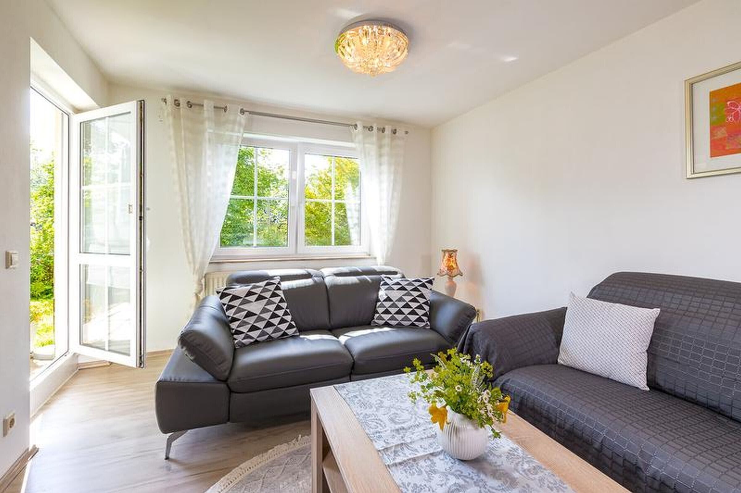 A modern living room with a sofa, a coffee table, and a window with curtains.