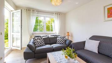 A modern living room with a sofa, a coffee table, and a window with curtains.