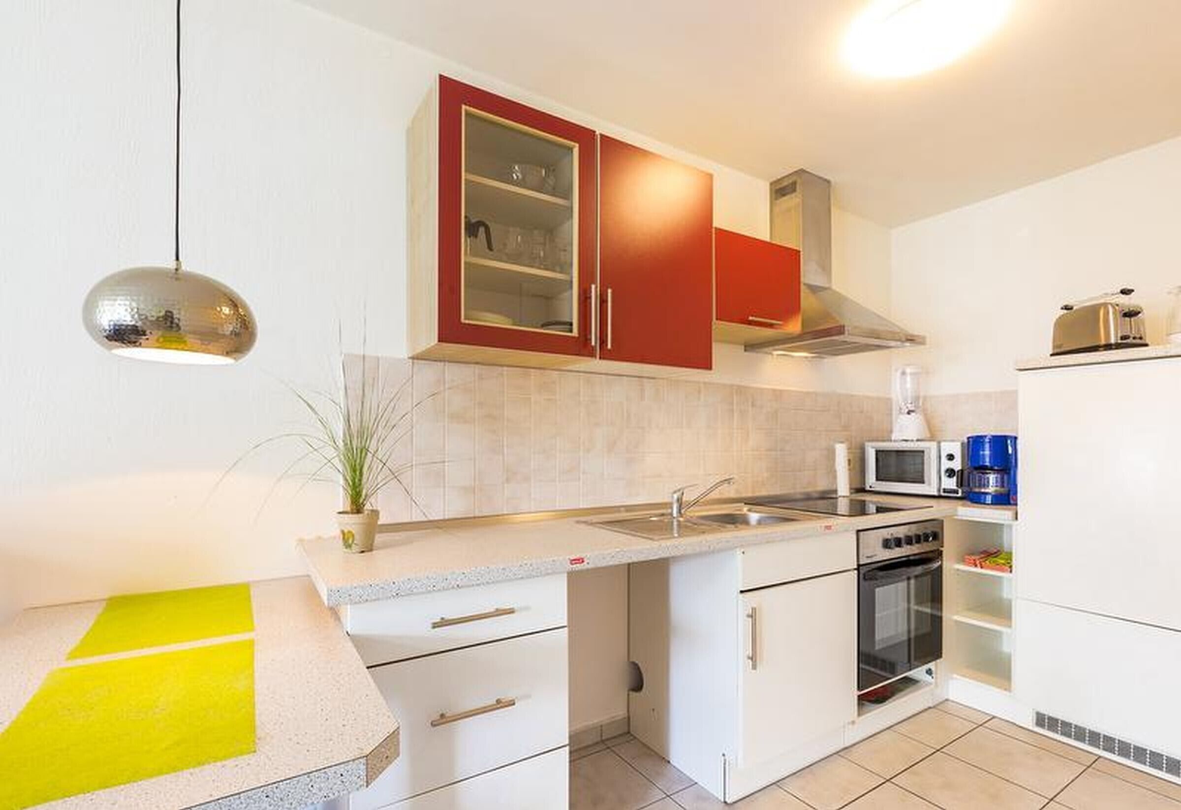 Een kleine keuken met een magnetron, broodrooster en oven.