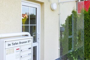 A mailbox outside a building with a door and window.