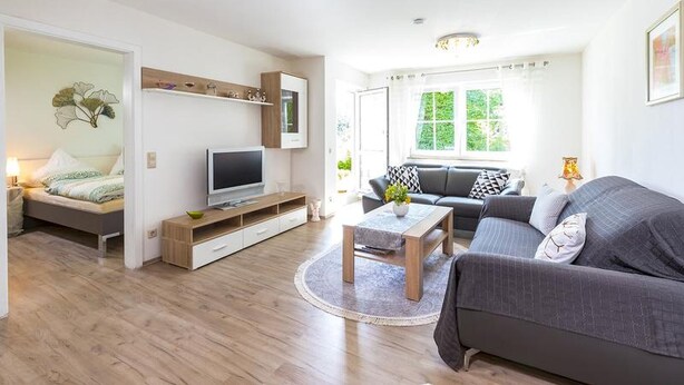 Una sala de estar moderna con un sofá, un televisor, una mesa de centro y una cama.