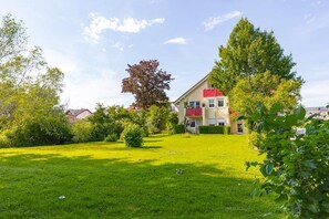 A house with a red roof, surrounded by a well-maintained lawn and trees.