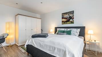 Een slaapkamer met een bed, nachtlampjes, een kledingkast en een schilderij aan de muur.
