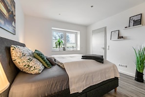 Une chambre à coucher moderne avec un lit, une fenêtre, une porte et une plante.
