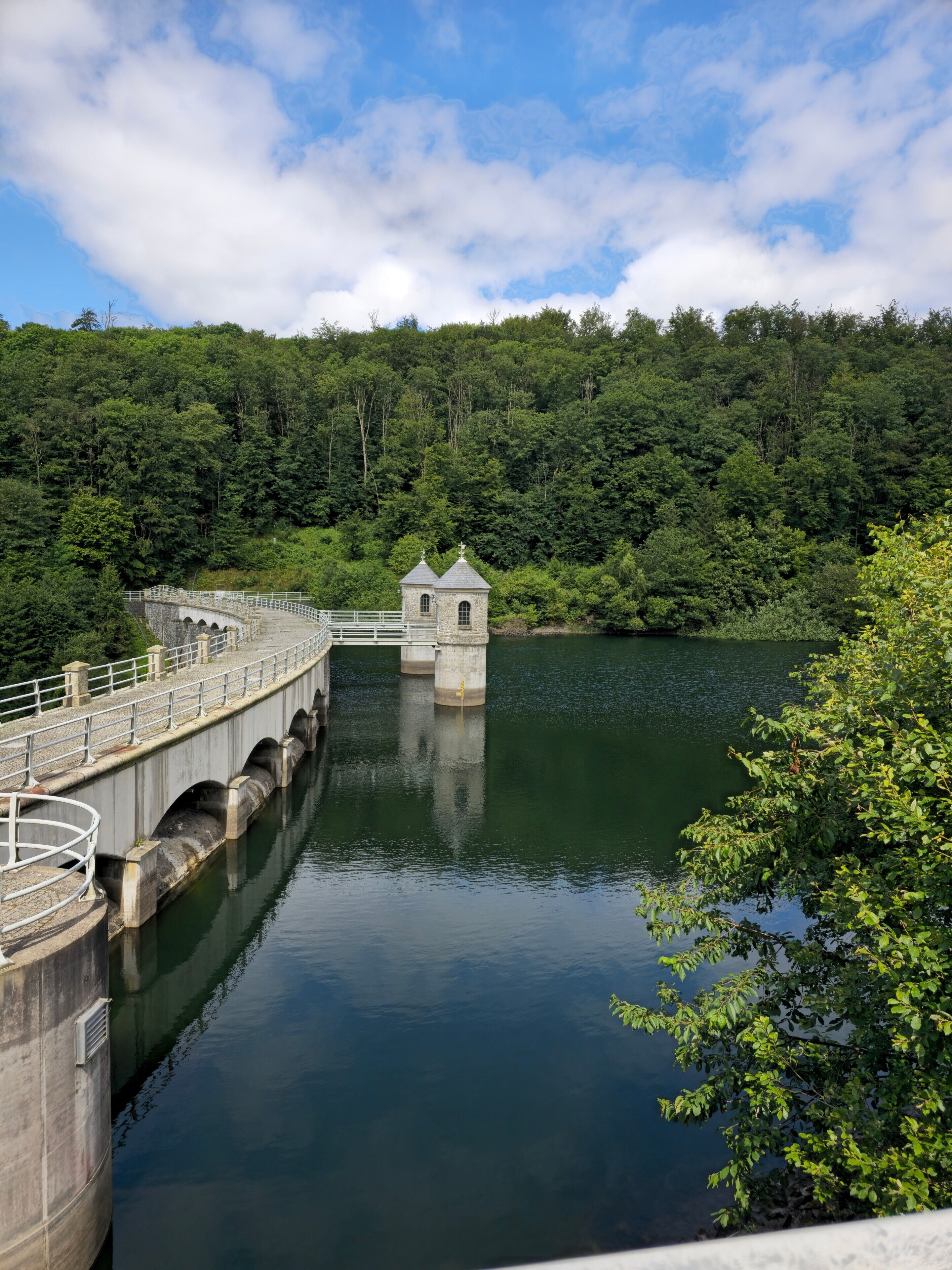 Eine Brücke mit einem kleinen Turm, umgeben von Wasser und Wald.