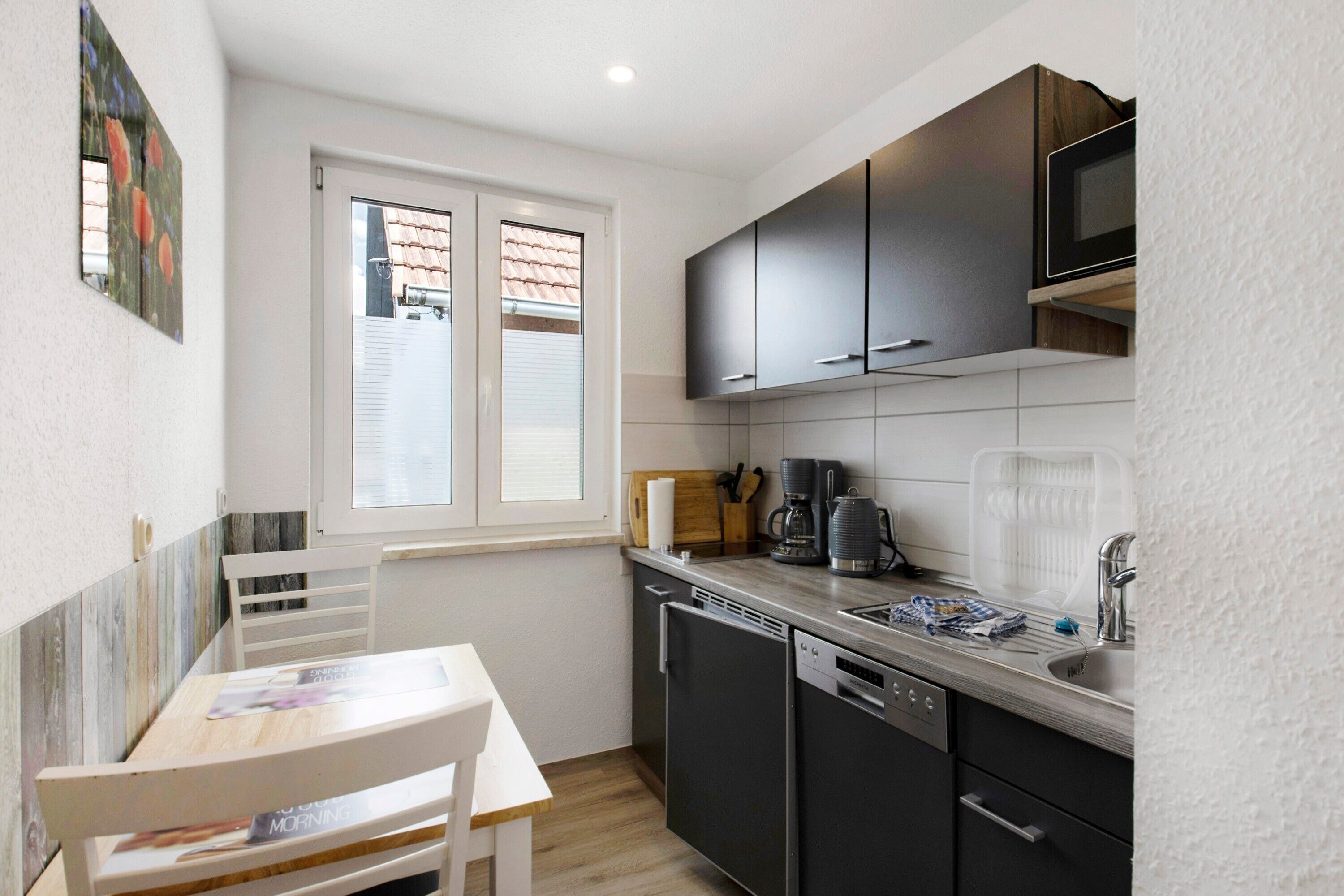 A compact kitchen with a dishwasher, a coffee maker, and a microwave.