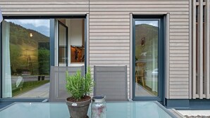 A modern building with large glass doors, a potted plant, and a glass table.