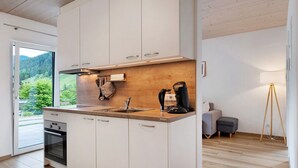 A modern kitchen with white cabinets, a wooden countertop, a built-in oven, and a coffee maker.