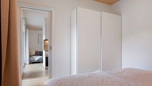 A bedroom with a bed, a wardrobe, and a door leading to another room.