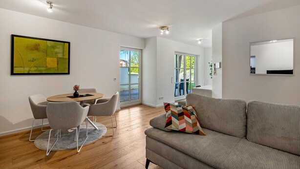 A modern living room with a sofa, a dining table with chairs, and a large window. - Apartment 'Naupenblick' with Private Terrace and Wi-Fi (Albstadt)