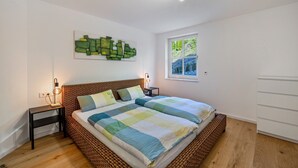 A bedroom with a bed, bedside tables, a wall art piece, a window, and a ceiling light fixture. - Apartment 'Naupenblick' with Private Terrace and Wi-Fi (Albstadt)