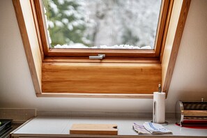 A skylight window with a wooden frame, a tissue roll, and a small wooden board on a white surface.