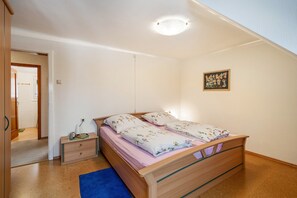 A bedroom with a wooden bed, a nightstand, a blue rug, and a painting on the wall. - Apartment 'Dachgeschoss' with Shared Terrace and Wi-Fi (Freudenstadt)