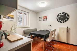 A kitchen with a cutting board, a kettle, and a wall clock.