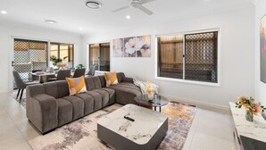 Un salon moderne avec un canapé d’angle, une table basse en marbre et un coin repas comprenant une table et des chaises.