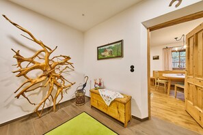 A room with a wooden tree sculpture, a bench with a cloth, a painting, and a dining area with wooden furniture. - Holiday Home Edt (Bad Goisern)
