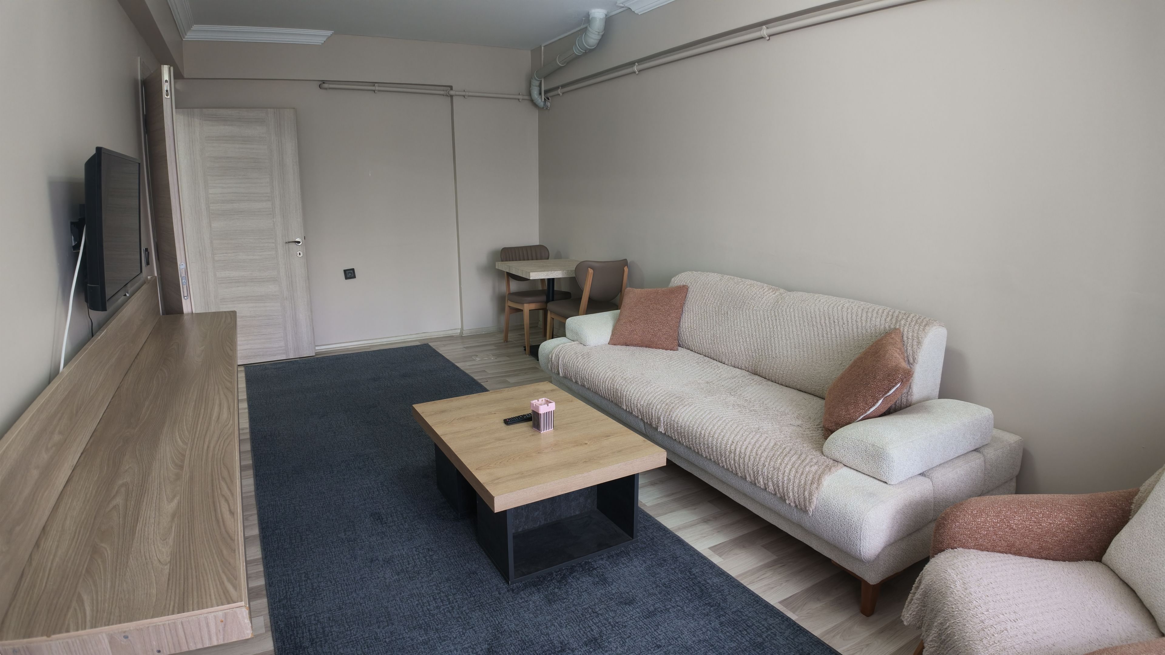 A living room with a sofa, a coffee table, a TV, and a door.