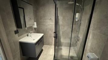 Een moderne badkamer met een douchecabine van glas, een wastafel met spiegel en een toilet.