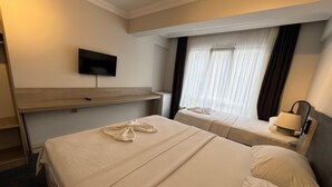 A hotel room with two beds, a flat-screen TV mounted on the wall, a bedside table with a lamp, and a window with curtains. - Viyana Boutique Otel (Kutahya)