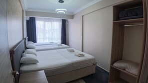 Una habitación de hotel con dos camas, un armario y una ventana con cortinas.