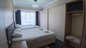 Una habitación de hotel con dos camas, un armario y una ventana con cortinas.