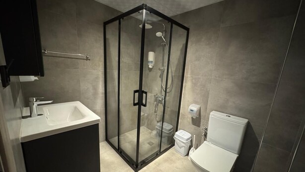 A modern bathroom with a glass-enclosed shower, a white sink, and a toilet. - Viyana Boutique Otel (Kutahya)