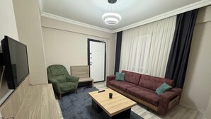 A modern living room with a sofa, armchair, coffee table, and a TV. - Viyana Boutique Otel (Kutahya)