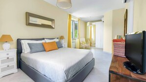 Un dormitorio moderno con una cama grande, mesitas de noche, un televisor de pantalla plana y una ventana con cortinas.