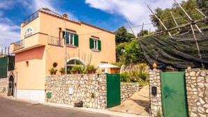 Un edificio de dos pisos con un muro de piedra y una verja verde.