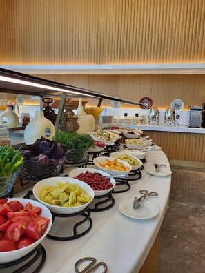 A buffet with various food items and a coffee machine.