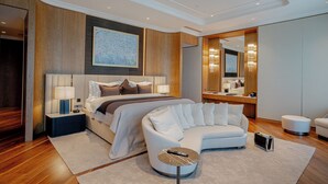 A modern hotel room with a large bed, a white sofa, a round coffee table, and a large mirror.