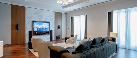 A modern living room with a large sofa, a flat-screen TV, and a marble accent wall.
