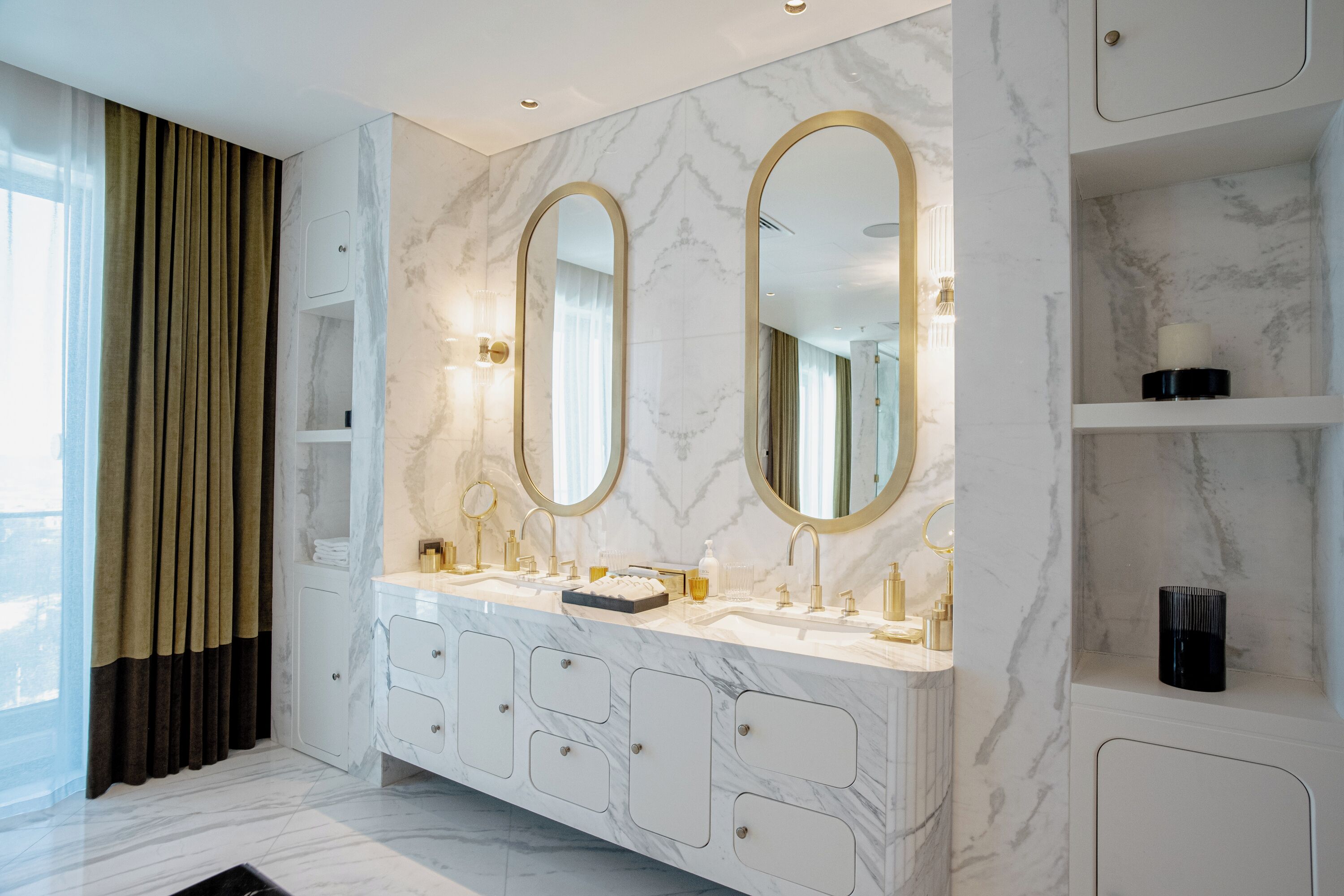 A modern bathroom with a marble vanity, dual sinks, and large mirrors.