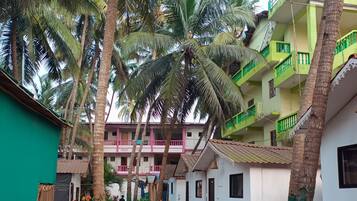 A courtyard with palm trees, a green building, and a multi-story structure with balconies.
