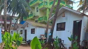 A courtyard with a white building, green balconies, and palm trees. - Love paradise  (Arambol)