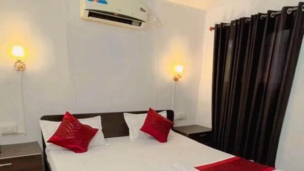 A hotel room with a bed, a red throw, a white pillow, a black headboard, a wall-mounted air conditioner, and a checkered floor. - Love paradise  (Arambol)