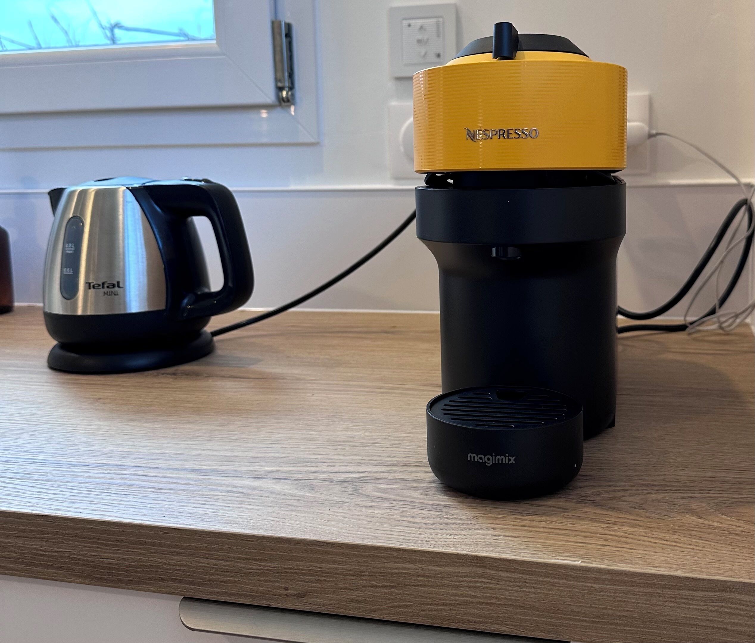 A coffee maker, a water bottle, and a mug on a wooden countertop.