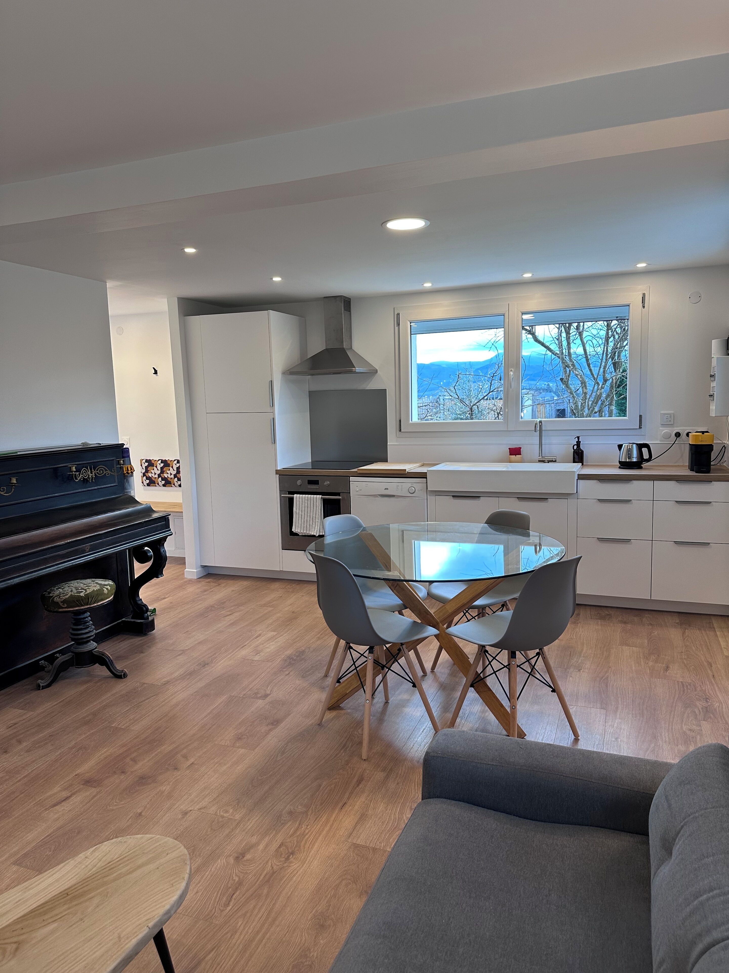 Une cuisine moderne avec un coin repas, un piano et une vue sur l’extérieur.