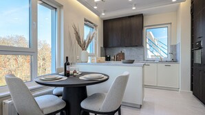 A modern kitchen with a central island, large windows, and a view of a bridge. - Crema Centrum Bydgoszczy Widok na Brd Gara (Bydgoszcz)