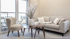 A modern living room with a sofa, armchair, and a small table with a vase of pampas grass. - Crema Centrum Bydgoszczy Widok na Brd Gara (Bydgoszcz)