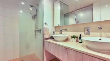A modern bathroom with two sinks, a large mirror, and a glass shower enclosure.