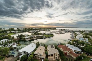A marina with boats, a large body of water, and residential buildings with solar panels.