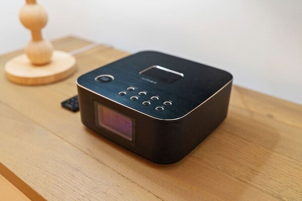 Un altavoz portátil negro con pantalla y botones sobre una superficie de madera.