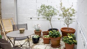Un patio con una mesa redonda, sillas y plantas en macetas.