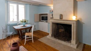 Una habitación con chimenea, una mesa de comedor con sillas, un televisor y una ventana con persianas.