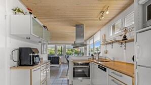 A modern kitchen with white cabinetry, a built-in oven, and a coffee maker.