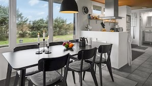 A modern kitchen with a central island, large windows, and a view of the outdoors.